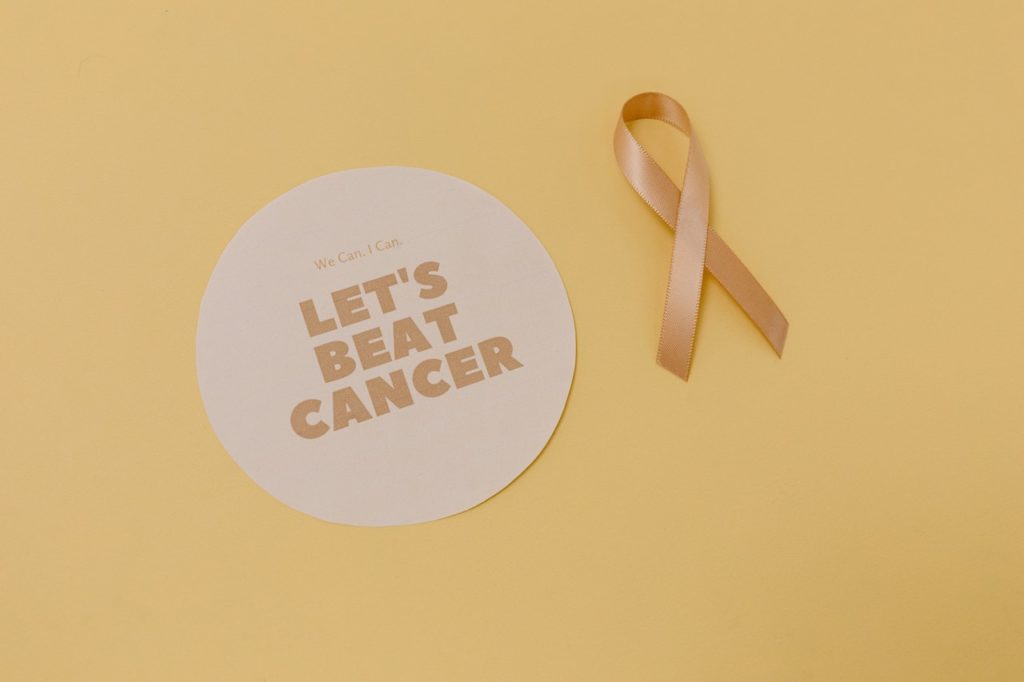 "Let's beat cancer"-Schild mit einer Schleife in gelbgold
